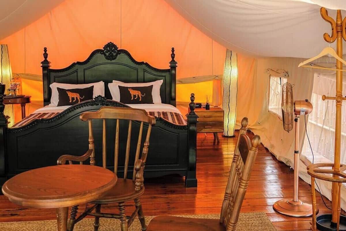 A bedroom with a large bed, a wooden chair, a table, and a lamp.