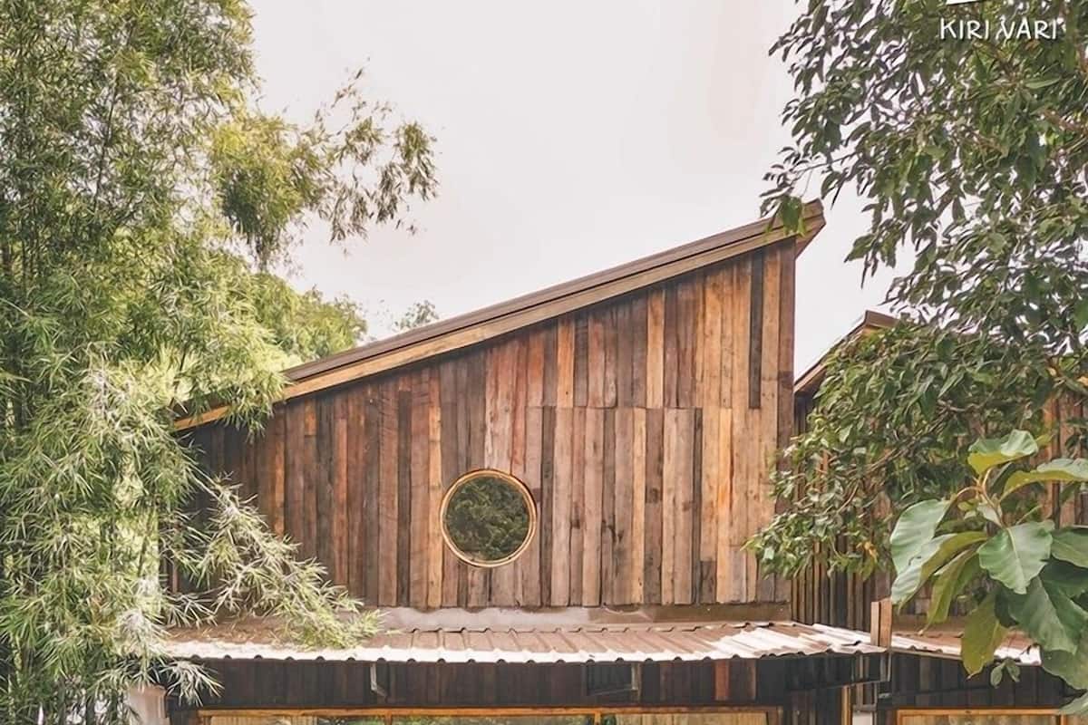 A wooden cabin with a balcony, furnished with chairs and a table.
