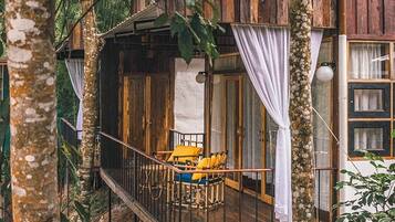 A wooden cabin with a balcony, surrounded by trees.
