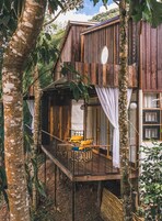 Una cabaña de madera con balcón, rodeada de árboles.