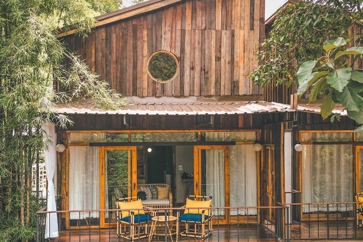 Una cabaña de madera con balcón, amueblada con sillas y una mesa.