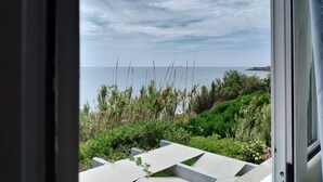 A view from a window overlooking a coastal landscape with a clear sky and calm sea. - SEAFRONT Duplex Apartment with Attic "MYRTO"—for up to 5 Guests (Korfu)