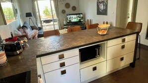 A modern kitchen with a central island, white cabinetry, and a dining area with chairs.