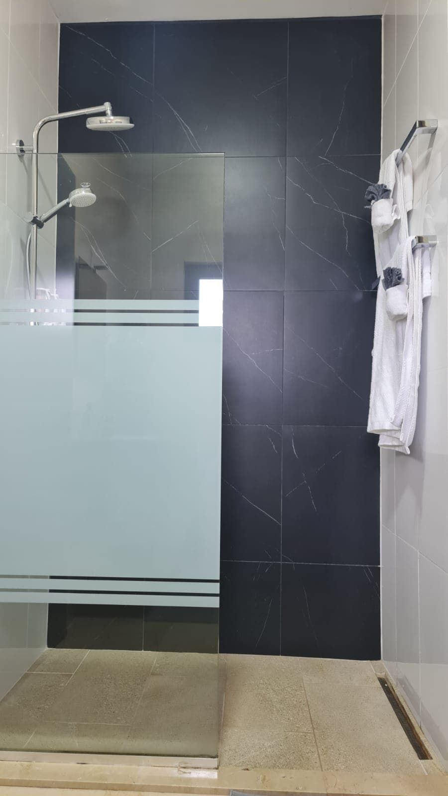 Une salle de bain moderne avec une douche à parois de verre, un lavabo blanc et un porte-serviettes.