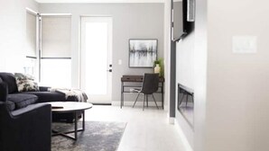 En moderne stue med sofa, sofabord og skrivebord med stol.