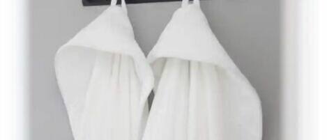 Una estructura metálica negra con dos batas blancas colgadas.