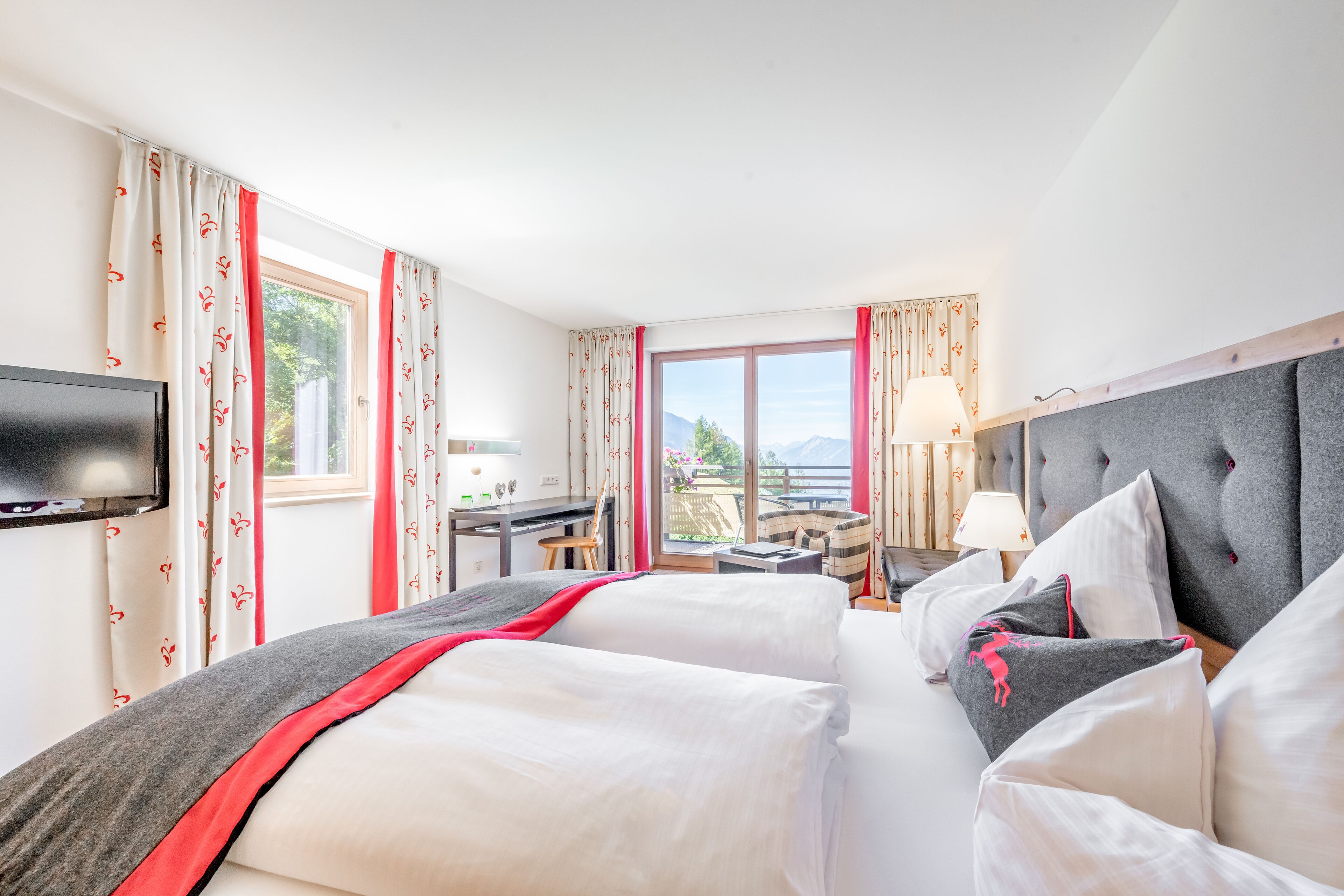 Habitación de hotel con dos camas, un escritorio, un televisor y vistas al exterior.