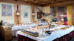 A buffet setup with various food items and a decorative branch overhead.