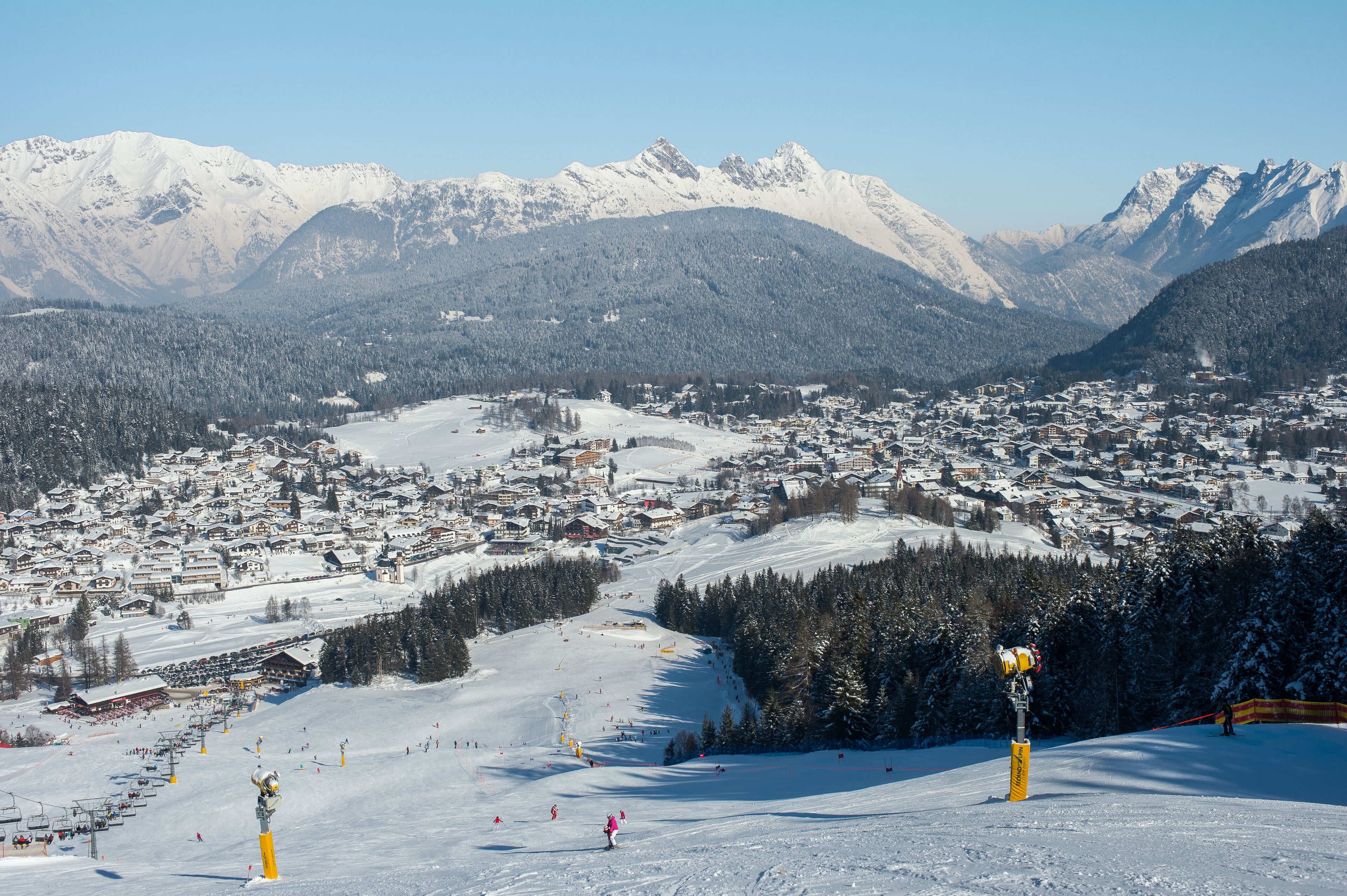 Eine verschneite Bergstadt mit Skipisten und freiem Blick auf die umliegenden Gipfel.
