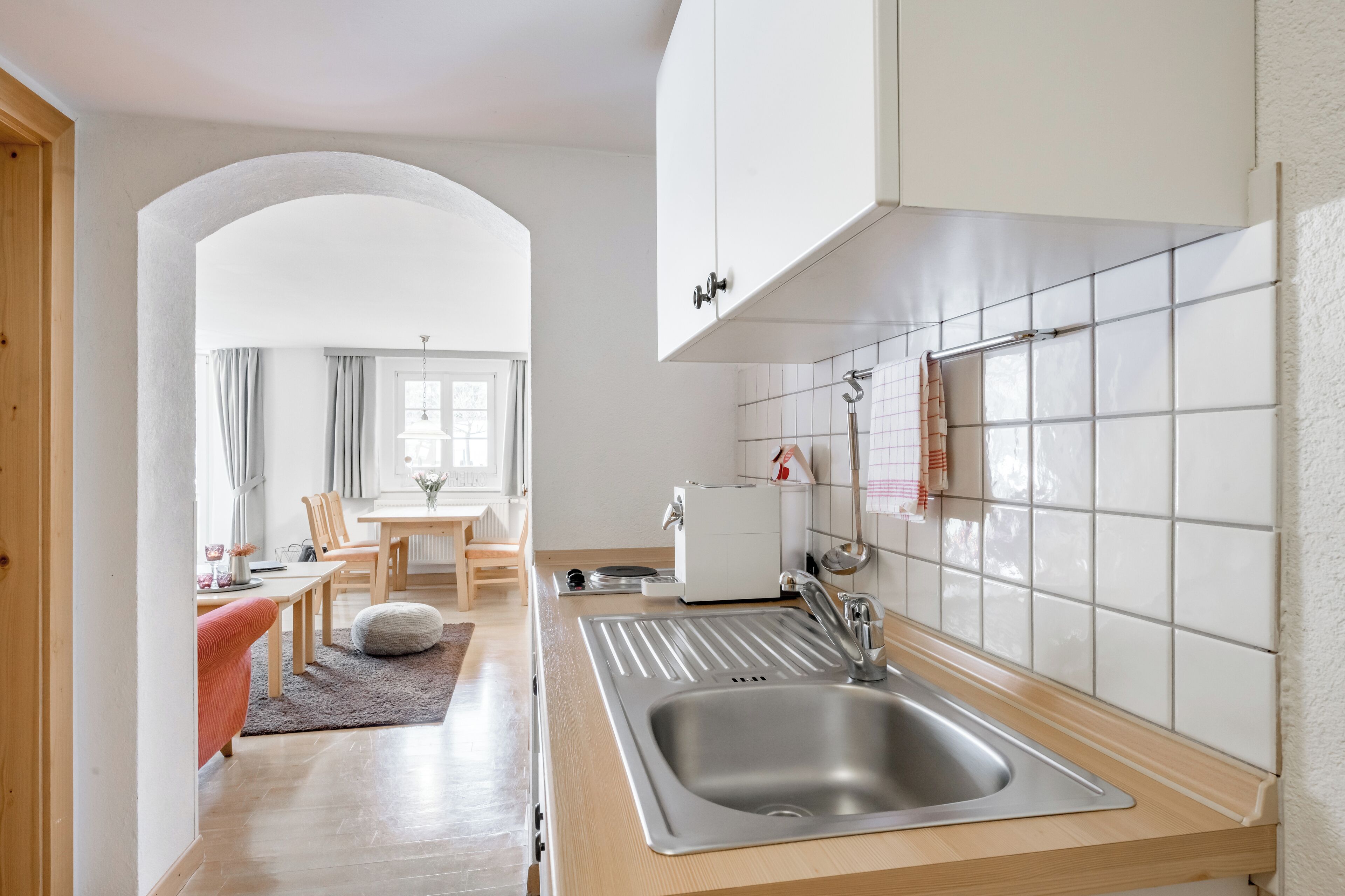 A modern kitchen with a stainless steel sink, wooden countertop, and white tiled backsplash.