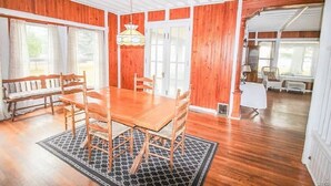 A dining area with a wooden table and chairs, a patterned rug, and a bench. - Historic Lake Front Home (Auburn)