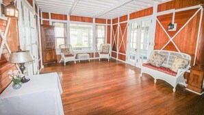 A room with wooden walls and floors, white furniture, and large windows. - Historic Lake Front Home (Auburn)