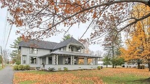 A two-story house with a porch and a covered front entrance. - Historic Lake Front Home (Auburn)