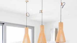 Een moderne keuken met witte aanrechtbladen, houten krukken en hanglampen.