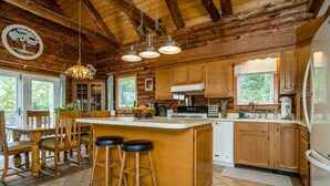 Une cuisine rustique avec des meubles en bois, un grand îlot central doté de tabourets et un luminaire suspendu.