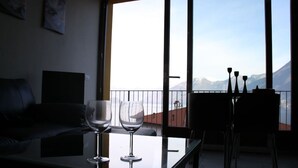 Een balkon met een tafel en twee wijnglazen, een bank, en een eethoek met stoelen en een tafel.