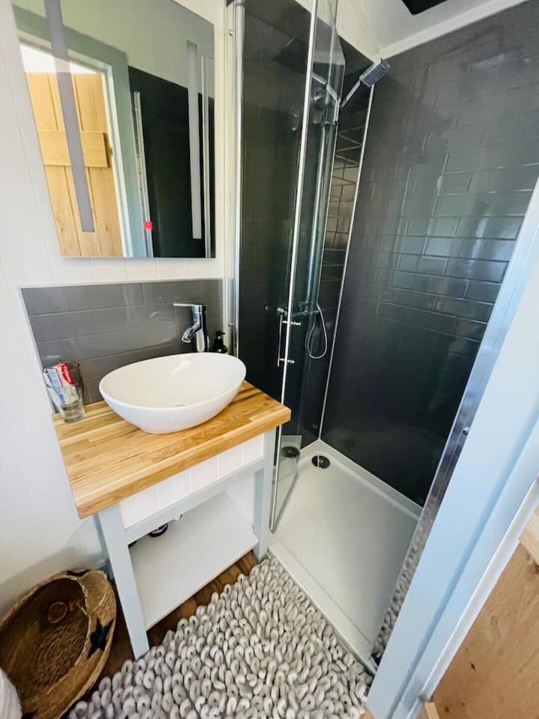 A modern bathroom with a white sink, wooden countertop, and a glass-enclosed shower.