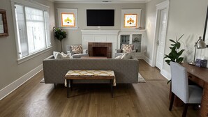 A living room with a fireplace, a sofa, a coffee table, and a TV mounted on the wall. - Craftsman house 500 yards to beach and short walk to many restaurants (Long Beach)