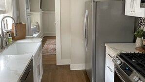 A modern kitchen with white cabinetry, a stainless steel refrigerator, a gas stove, and a dishwasher. - Craftsman house 500 yards to beach and short walk to many restaurants (Long Beach)