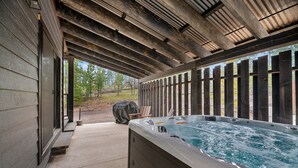 A hot tub under a covered patio with a view of a wooded area. - Summit Sunset, pet friendly! Hot Tub, Pool access, paved roads, luxury finishes (Lead)