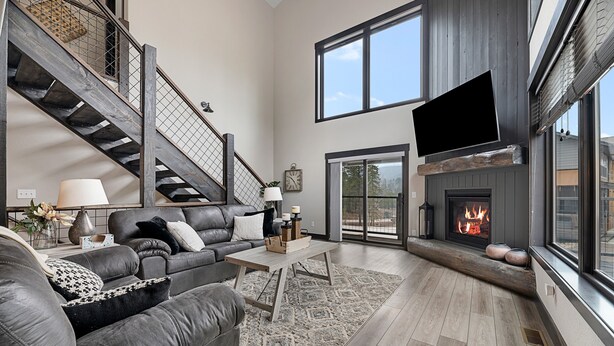 A spacious living room with a fireplace, leather sofas, a coffee table, and a staircase. - Summit Sunset, pet friendly! Hot Tub, Pool access, paved roads, luxury finishes (Lead)