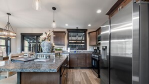A modern kitchen with granite countertops, stainless steel appliances, and wooden flooring. - Summit Sunset, pet friendly! Hot Tub, Pool access, paved roads, luxury finishes (Lead)