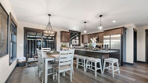 A modern kitchen with wooden flooring, white cabinetry, and stainless steel appliances. - Summit Sunset, pet friendly! Hot Tub, Pool access, paved roads, luxury finishes (Lead)