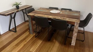 A dining table with six chairs, a potted plant, and a rustic wooden table top. - Recovery On Discovery Holiday House (Agnes Water)