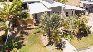 A modern residential area with detached houses, well-maintained lawns, and tropical plants. - Recovery On Discovery Holiday House (Agnes Water)