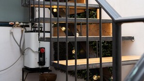Een trap met houten treden en zwarte metalen leuningen, die uitkomt op een plateau met een witte muur en een waterdispenser.