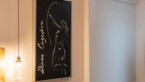 Een kamer met een bed, een grijze bank, een aan de muur hangend kunstwerk, een hanglamp en een inbouwspot.