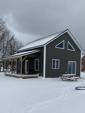 Cozy single-story building with a covered porch and bench, surrounded by a serene winter landscape.
