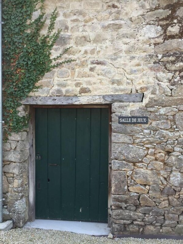 A stone building with a green door and a sign reading "SALLE DE JEUX".