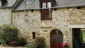 A stone building with a red door, a small window, and a sign that reads "Clement".