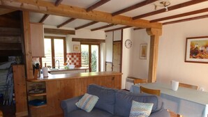 A cozy living room with a sofa, a dining table, and a kitchen area.