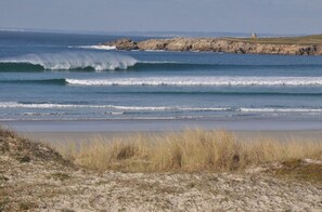 A beach with waves, rocky outcrops, and a grassy area.