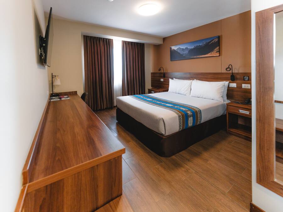 Ein Hotelzimmer mit einem großen Bett, einer Holzbank und einem Bild an der Wand.