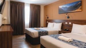Een hotelkamer met twee bedden, een bureau, een televisie en een schilderij aan de muur.