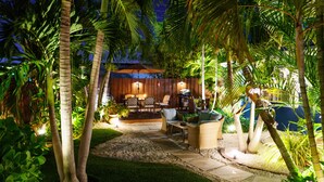 An outdoor patio area with a wooden deck, seating, and a barbecue setup. - Modern Oasis (Oakland Park)