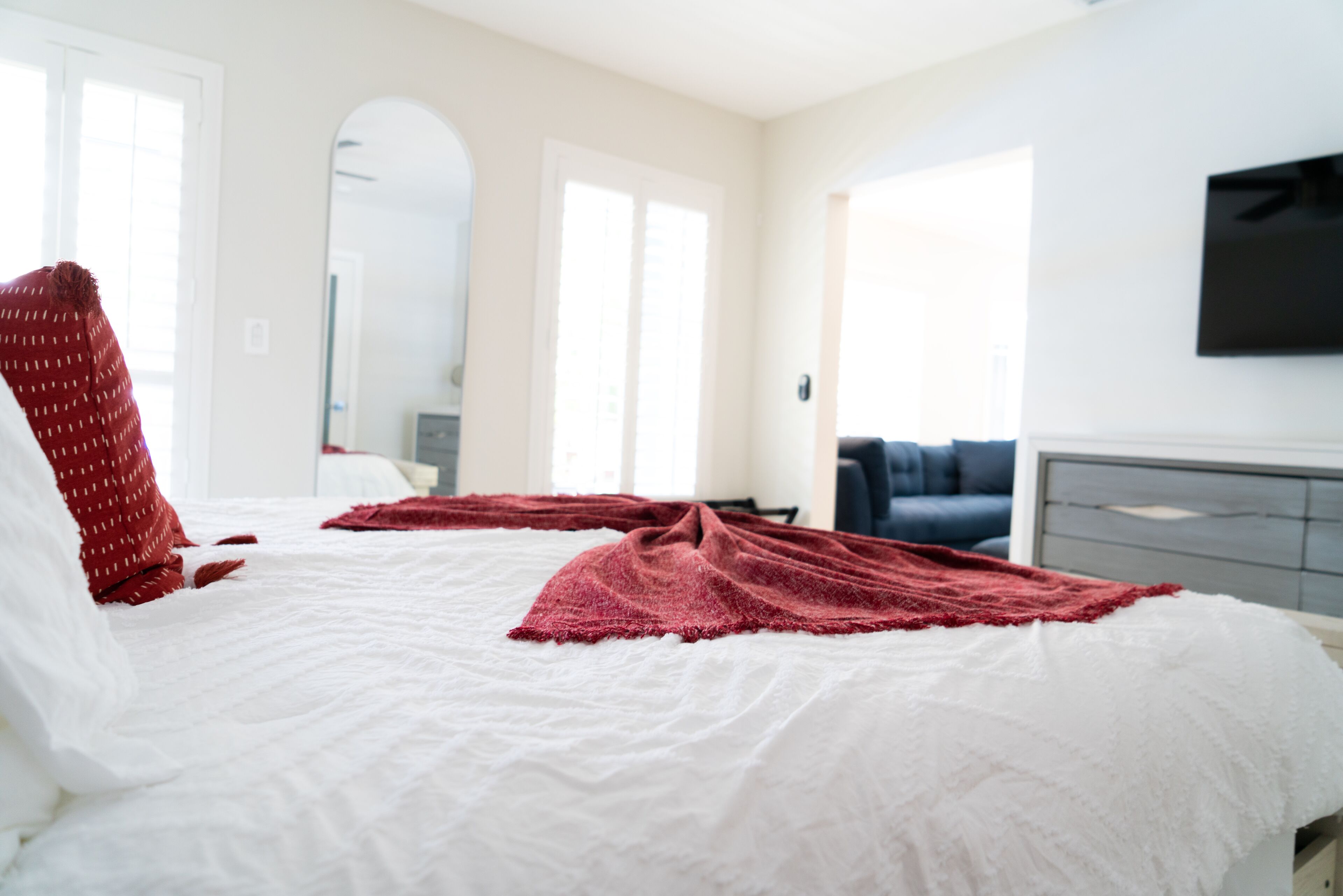 A hotel room with a large bed, a flat-screen TV mounted on the wall, and a view of the outside through the window.