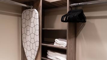 A closet with wooden shelves, a hanging rack, and an ironing board.
