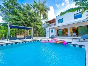 A modern pool area with a clear blue pool, lounge chairs, and a covered seating area. - Luxury “ART DECO”Villa Waterfront POOL ❤️ (Miami)