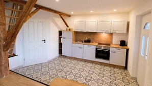 Eine Küche mit weißen Schränken, einer Holz Arbeitsplatte und einem gemusterten Boden.