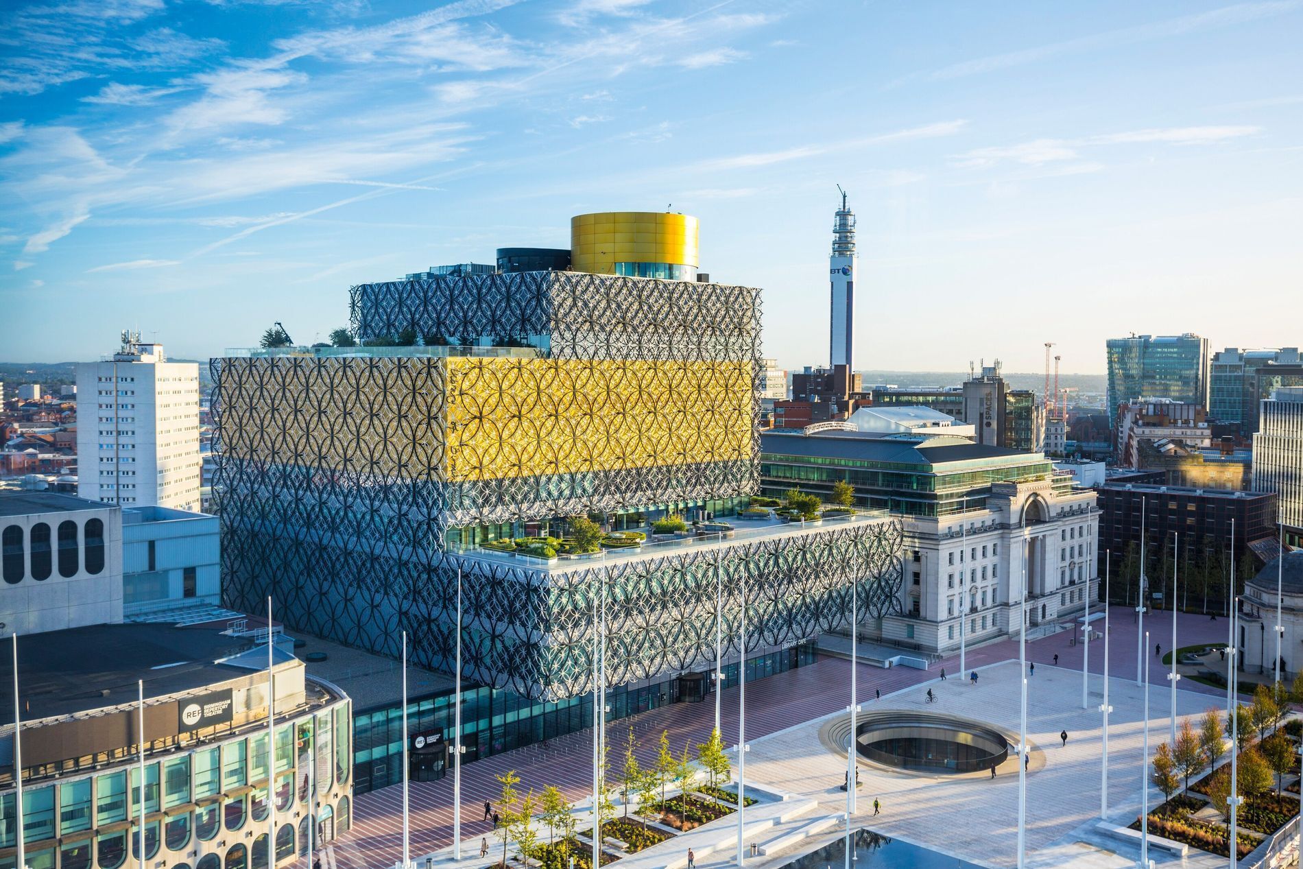 A modern building with a unique geometric facade, surrounded by other urban structures.
