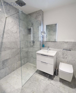 A modern bathroom with a glass-enclosed shower, a white sink, and a toilet. - Stunning Penthouse - Birmingham City Centre (Birmingham)