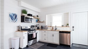 Une cuisine moderne avec des meubles blancs, un lave-vaisselle en acier inoxydable et un plan de travail noir.