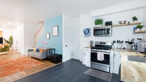 Une cuisine moderne avec des meubles blancs, une cuisinière en acier inoxydable et un four à micro-ondes. On y trouve un plan de travail en bois et un évier.