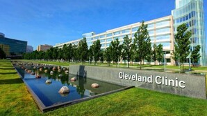 Un edificio moderno con un cartel que dice "Cleveland Clinic" y un área ajardinada con fuente de agua.
