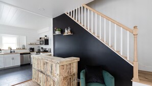 Una cocina moderna con armarios blancos, una isla de madera y una pared de acento negra.