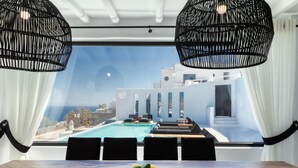 Un comedor moderno con vistas a una piscina y al horizonte urbano.